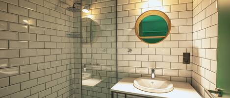 Een moderne badkamer met witte metrotegels, een douche met glazen wanden, een ronde spiegel en een witte wasbak.