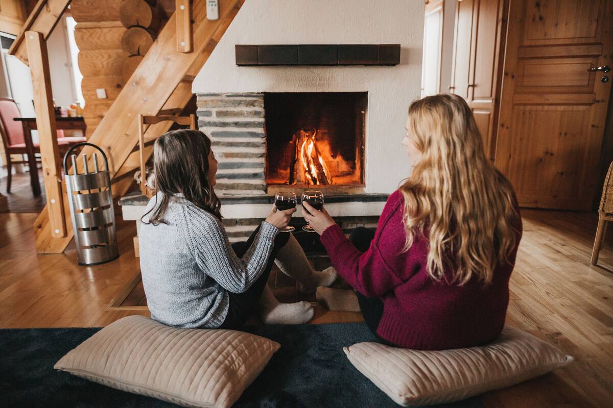 Two people sitting on the floor in front of a fireplace with a stone surround.