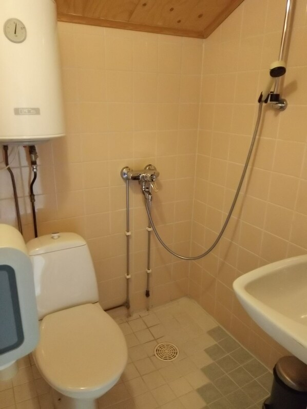 Une petite salle de bain avec des toilettes, une douche et un lavabo.