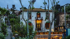 A hotel with a balcony, a stone facade, and a view of a mosque in the background. - No 2 Hotel By Şükrü (Adalar)