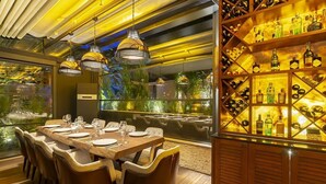A dining area with a long table set for six, surrounded by chairs, and a wine display case to the right. - No 2 Hotel By Şükrü (Adalar)