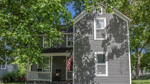A two-story house with a porch, a small garden, and an American flag. - Large home, Pet friendly (Union)