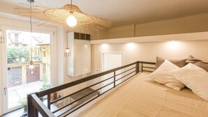 Un dormitorio moderno con una cama grande, un balcón y una lámpara colgante.
