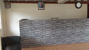 Zona de recepción con pared de piedra, un retrato enmarcado y un reloj en la pared.