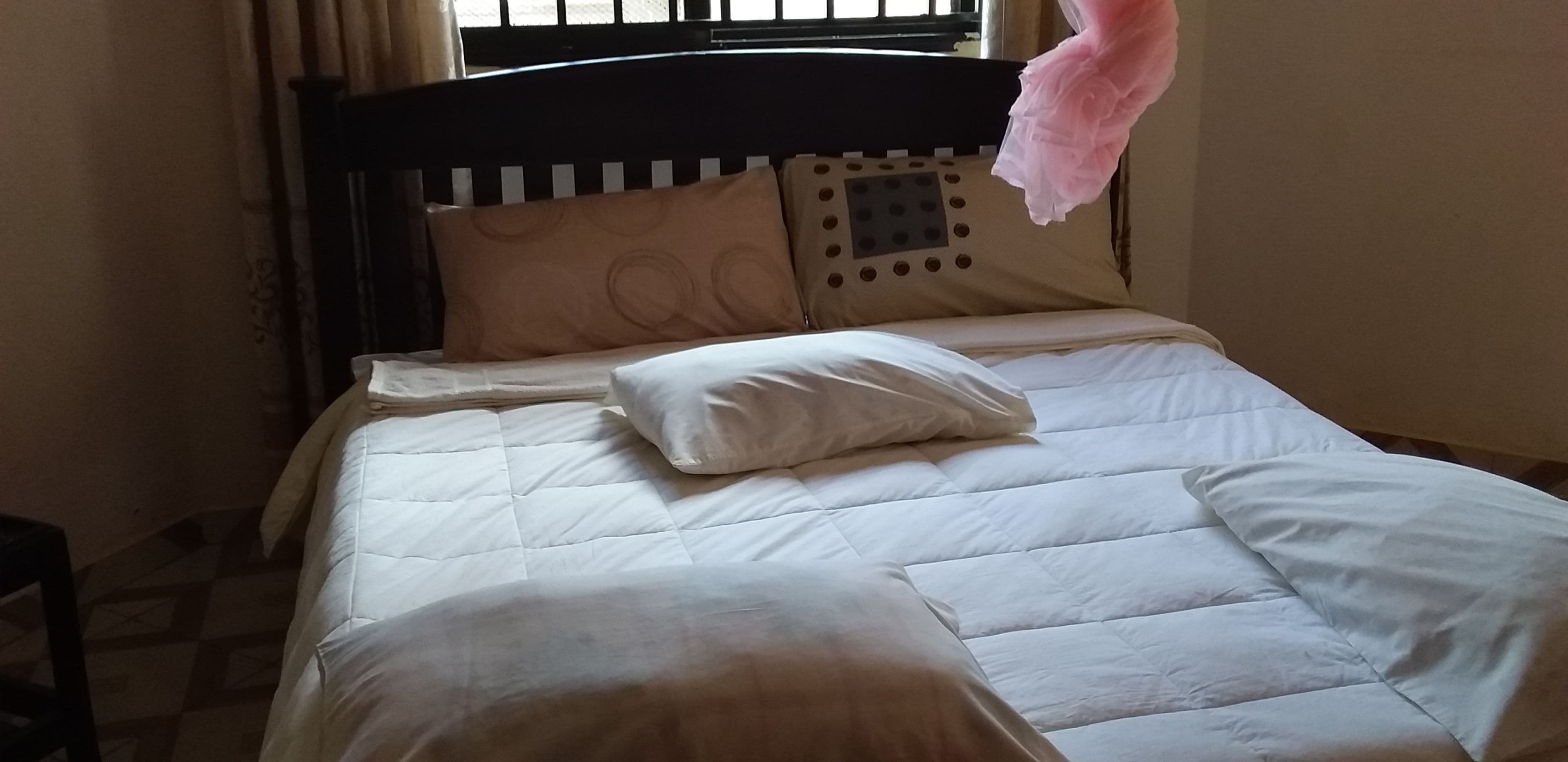 Una cama con edredón blanco acolchado, una almohada blanca y un cabecero con un panel decorativo.