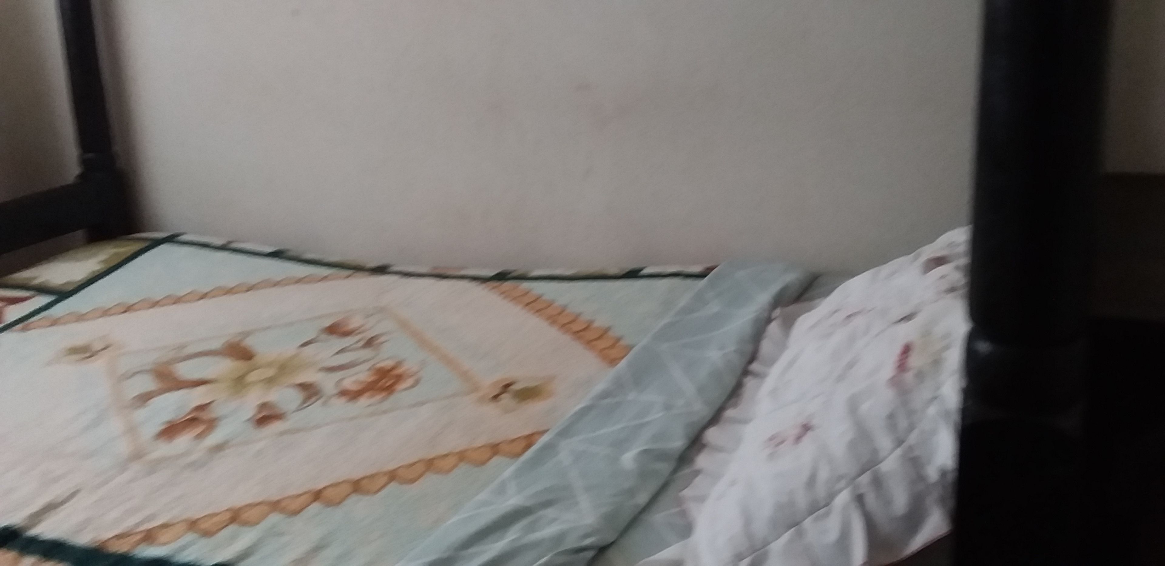 Una cama con una colcha estampada con motivos florales y una almohada lisa.
