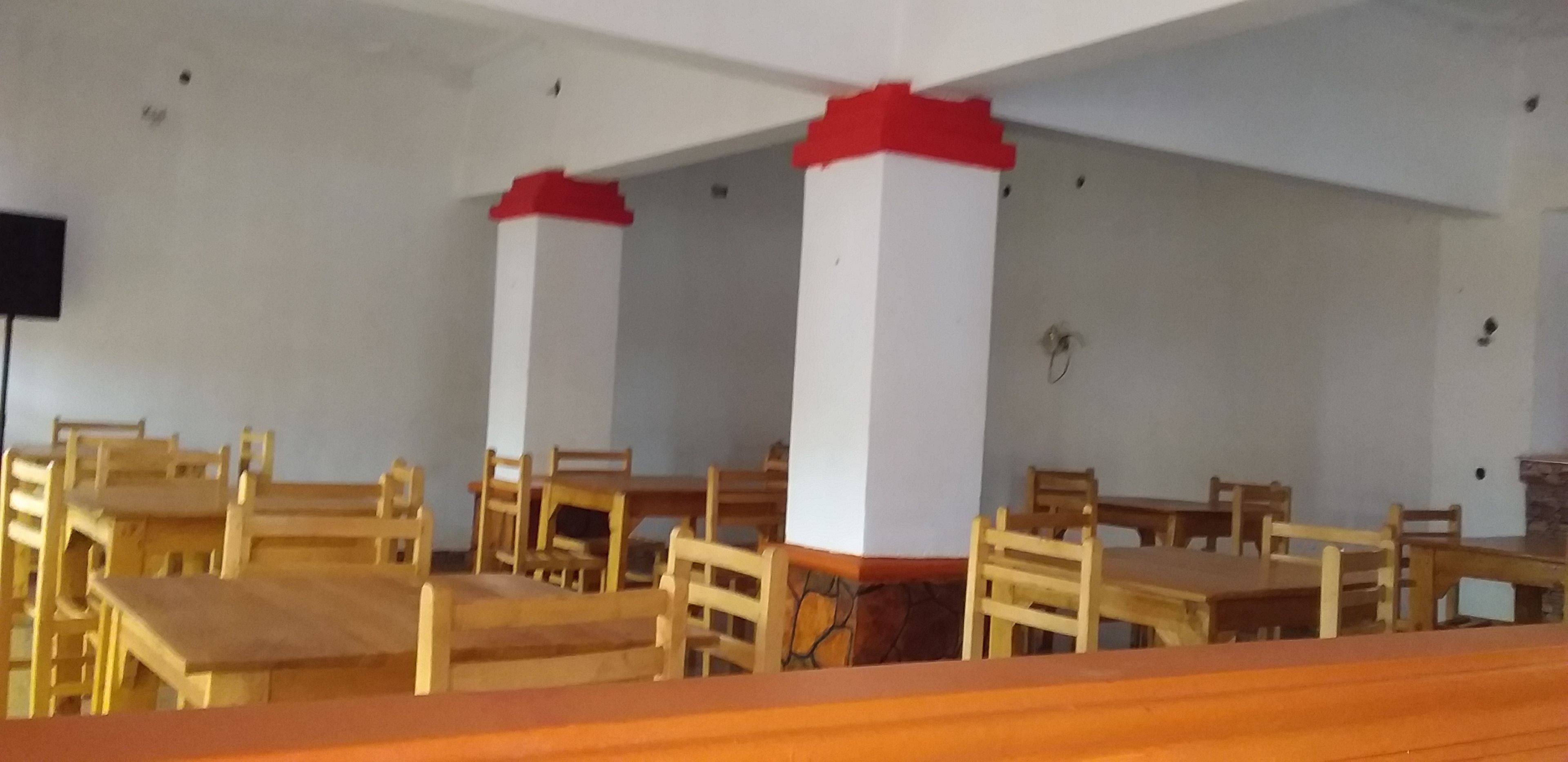 A room with wooden tables and chairs, white walls, and red accents on the columns.