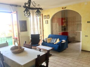 A living room with a blue sofa, a dining table with a basket, and a chair. - Forte dei Marmi apartment (Massa)