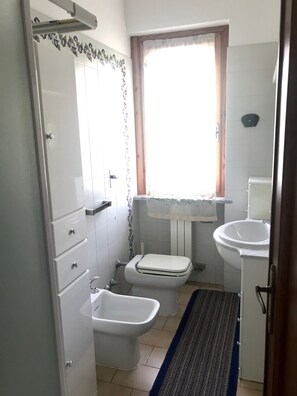 A compact bathroom with a toilet, bidet, and sink.