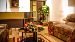 A reception area with a reception desk, a round table with a vase of flowers, a brown leather sofa, and a potted plant. - Mbale Travellers Inn (Mbale)