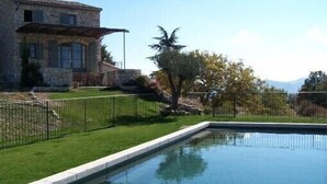 A stone building with a pool and a fenced yard. - Stone barn 360 ° view of the Luberon and the Vaucluse mountains (Viens)