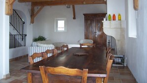 A dining room with a large wooden table, chairs, a staircase, and a window. - Stone barn 360 ° view of the Luberon and the Vaucluse mountains (Viens)