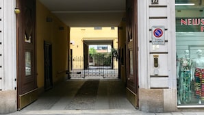A building entrance with a metal gate, a sign indicating a no parking zone, and a storefront with mannequins. - Sarpi Apartment (Milan)