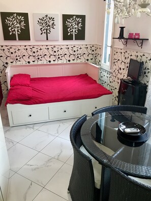 A bedroom with a bed, a glass table with a telephone, and wall art. - Sarpi Apartment (Milan)