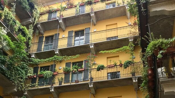 A multi-story building with balconies adorned with potted plants and greenery. - Sarpi Apartment (Milan)