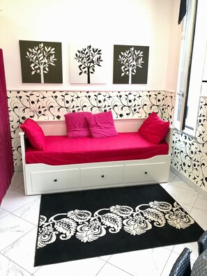 A room with a white bed with red bedding, a black and white patterned rug, and three wall-mounted paintings of trees. - Sarpi Apartment (Milan)