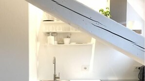 Uma cozinha moderna com armários brancos, forno embutido e pia.