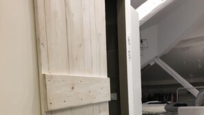 Quarto com porta de madeira, cama beliche e sofá.