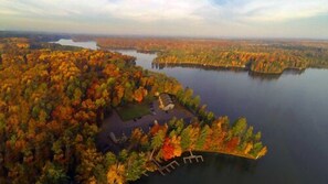 An aerial view of a lakeside property surrounded by autumn foliage.