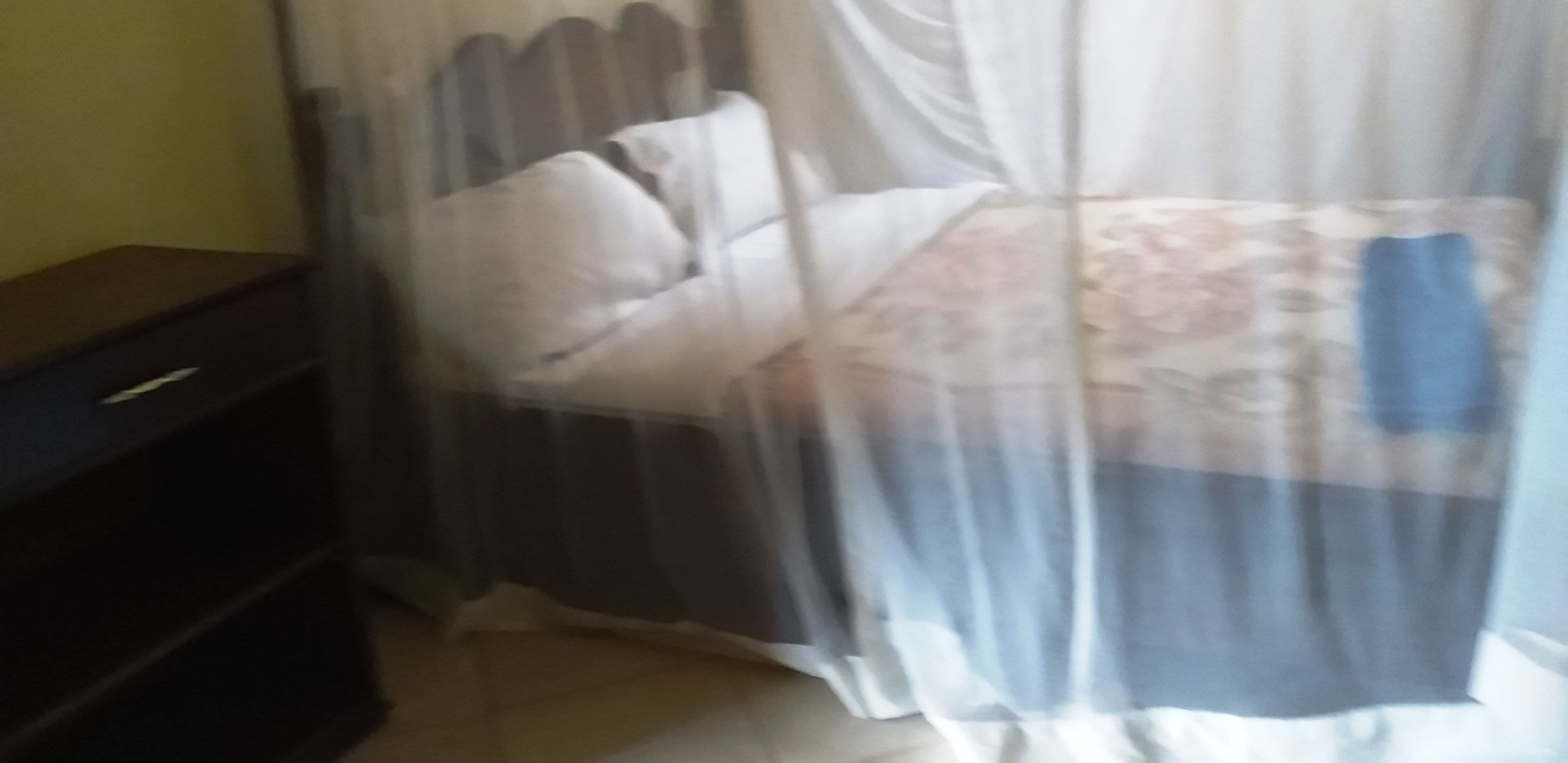 A bed with a patterned bedspread, a bedside table, and a curtain.