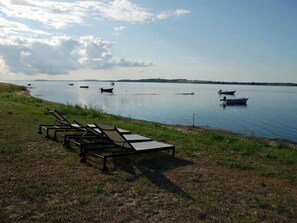 Un entorno junto al lago con sillones de descanso y barcos en el agua.