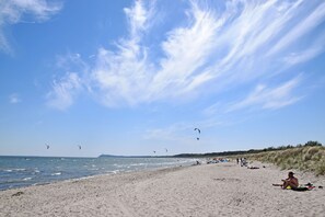 Ein Strand mit Sand, Wasser und Drachen.