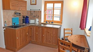 Una cucina con mobili in legno, una finestra, un lavello e un tavolo da pranzo con sedie.
