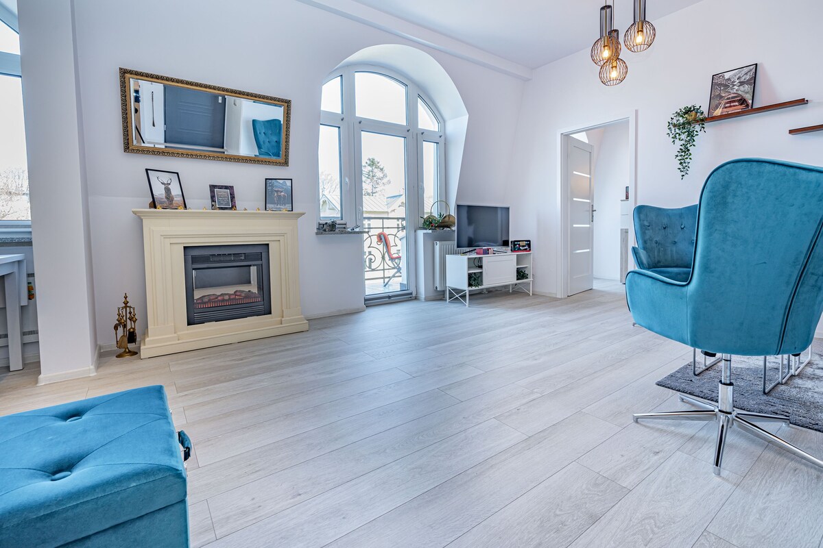 Uma sala de estar moderna com lareira, televisão e uma poltrona azul.