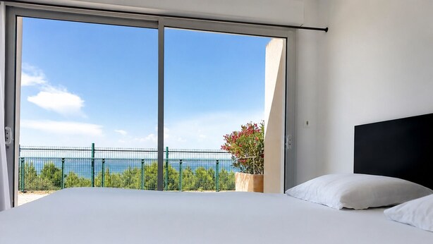 A bedroom with a large bed, a view of the sea, and a balcony with a railing. - Appart'hotel Résidence La Provence (Saint-Mitre-les-Remparts)