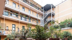 A multi-story building with balconies, potted plants, and a staircase. - Corso Buenos Aires 35 (Milan)