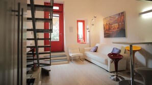 A modern living room with a white sofa, a red door, and a cityscape painting. - Corso Buenos Aires 35 (Milan)