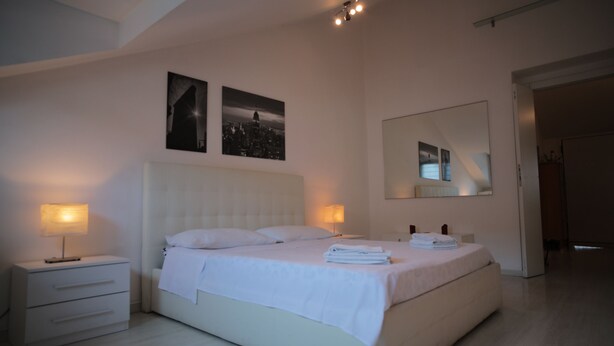 A modern bedroom with a large bed, bedside tables, and wall-mounted artwork. - Corso Buenos Aires 35 (Milan)