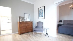 Un dormitorio con cama, cómoda, silla y una pequeña mesa.