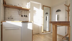 Una cocina compacta con armarios blancos, lavavajillas integrado y encimera de madera.