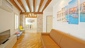 A modern living room with a wooden ceiling, a stone wall, and a large window. - DolceVita Apartments N. 393 (Venice)