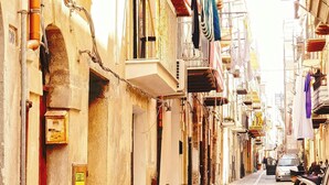 A narrow cobblestone street lined with buildings, some with balconies and hanging laundry. - Modular House - Alessandro (Cefalù)