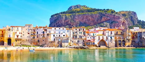 Un pueblo costero con edificios históricos, una playa y un acantilado imponente.