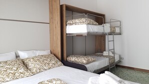 A bunk bed room with a wooden headboard, white bedding, and patterned pillows. - Modular House - Alessandro (Cefalù)