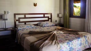Una cama con cabecera de madera, ropa de cama floral y un adorno en la pared.
