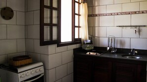 Una cocina con estufa, lavabo y ventana con cortinas.
