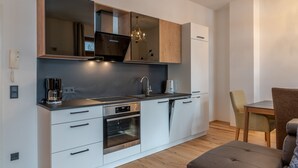 A modern kitchen with built-in appliances, a dining area with a table and chairs, and a chandelier. - Post Residence Apartments 2B, sauna, SUMMER CARD (Zell am See)