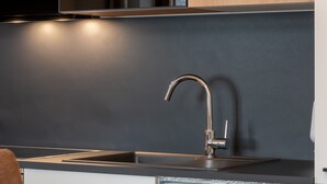 A modern kitchen with a stainless steel sink, a sleek faucet, and a dark backsplash. - Post Residence Apartments 2B, sauna, SUMMER CARD (Zell am See)