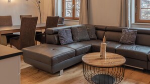 A modern living room with a sectional sofa, a round coffee table, and a dining area with chairs and a table. - Post Residence Apartments 2B, sauna, SUMMER CARD (Zell am See)