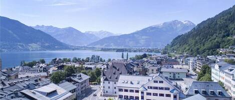 A town with buildings along a waterfront, surrounded by mountains and a lake.
