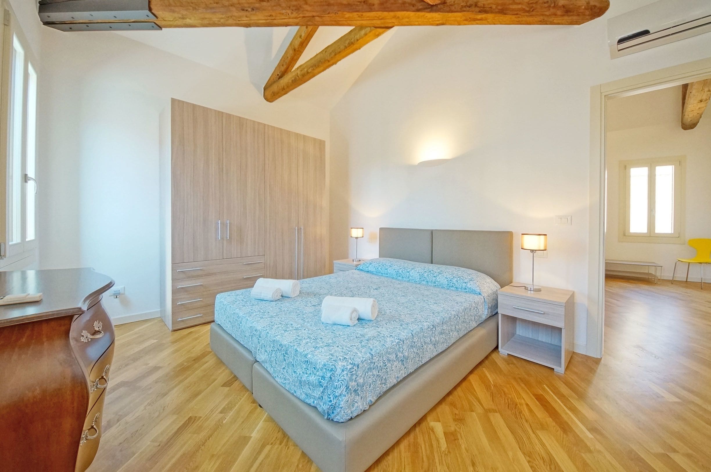 Un dormitorio con cama, mesitas de noche, un armario y un espejo.