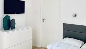 Une chambre à coucher avec un lit, une commode, un téléviseur et une porte.