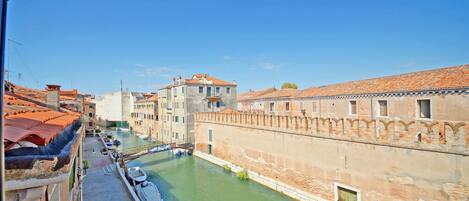 A canal with boats, historic buildings, and a clear blue sky.