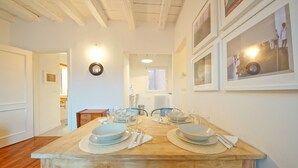 A dining area with a wooden table set for four, chairs, and framed pictures on the wall. - DolceVita Apartments N. 396 (Venice)