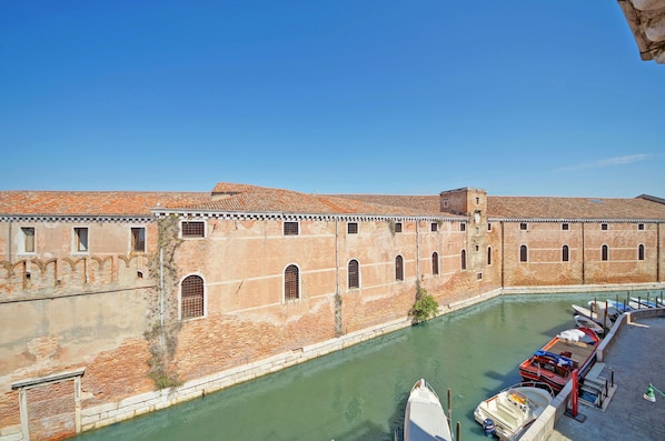A historic building with a canal and boats docked in front.