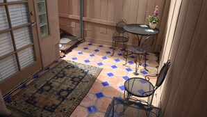 En terrasse med flisegulv, et bord med stole og en plantekasse.